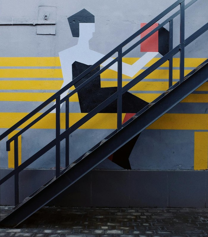 Steel staircase on a modern mural wall, showcasing artistic urban design with bold colors.